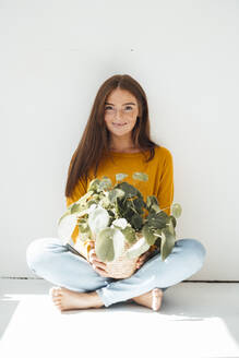 Lächelnde Frau mit Topfpflanze vor einer Mauer - JOSEF07201