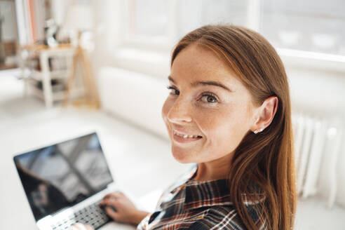 Lächelnde Frau mit Laptop zu Hause - JOSEF07210