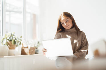 Junge Frau benutzt Laptop zu Hause - JOSEF07212