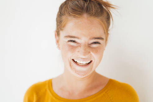 Young woman laughing in front of white background - JOSEF07236