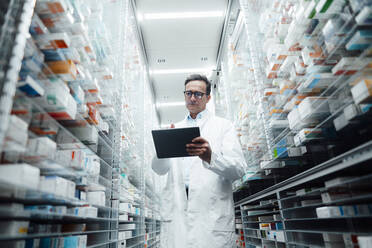 Pharmacist with tablet computer taking inventory in pharmacy - JOSEF07264