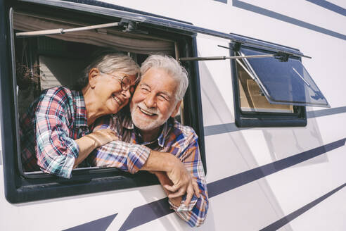 Smiling senior woman leaning on man looking through window of motor home - SIPF02756