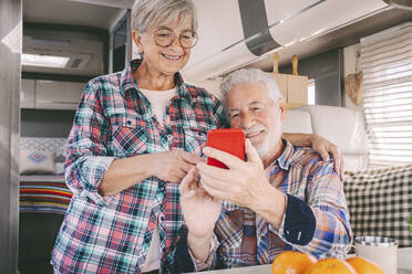 Lächelndes älteres Paar, das ein Smartphone im Wohnmobil benutzt - SIPF02762