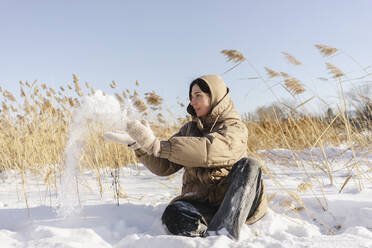 Frau spielt mit Schnee auf einem Feld - SEAF00607