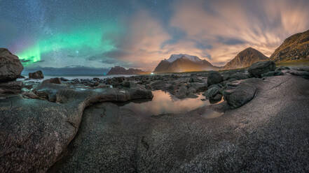 Die malerische Landschaft der felsigen Küste, die von der endlosen Nordsee umspült wird, unter bunten Polarlichtern bei Nacht auf der Insel Lofoten in der Nähe der Berge - ADSF33693