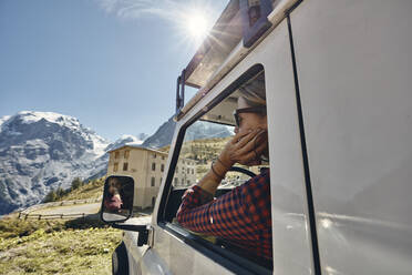 Woman looking through window of off-road vehicle on road trip, Passo dello Stelvio, South Tyrol, Italy - SSCF00838