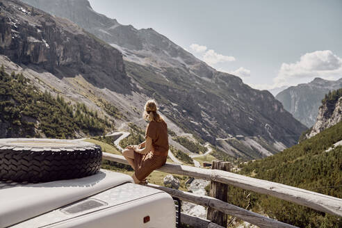 Tourist auf Holzgeländer sitzend mit Geländewagen, Stilfser Joch, Südtirol, Italien - SSCF00844
