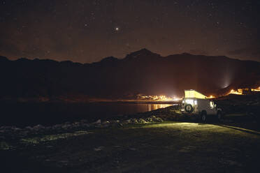 Beleuchteter Geländewagen am Stausee bei Nacht, Splugenpass, Sondrio, Schweiz - SSCF00853