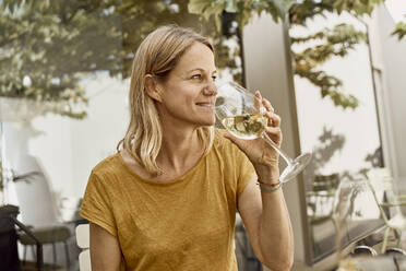 Smiling woman drinking wine at restaurant - SSCF00916