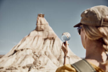 Frau betrachtet Berg durch Vergrößerungsglas an sonnigem Tag - SSCF00922