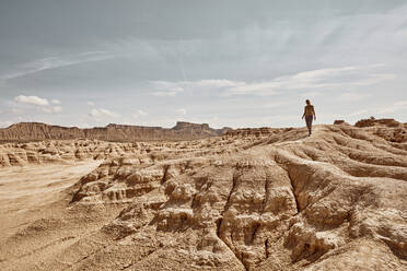 Frau, die auf einer Felsformation in der Wüste bei Bardenas Reales, Spanien, spazieren geht - SSCF00946