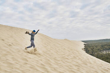 Cheerful woman running on sand dune - SSCF00975