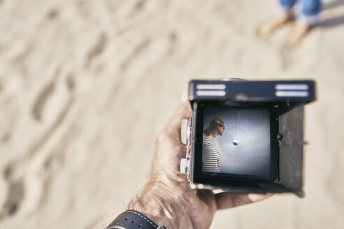 Mann hält Vintage-Kamera mit Frau Bild auf sie am Strand - SSCF01012