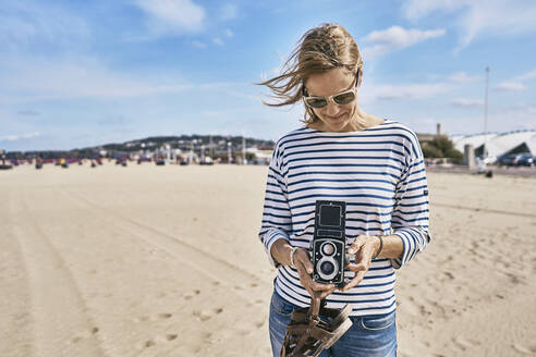 Tourist mit Oldtimer-Kamera steht am Strand an einem sonnigen Tag - SSCF01013