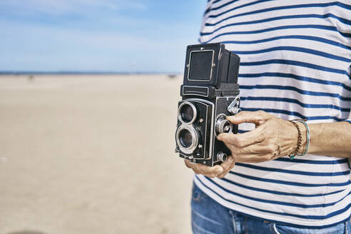 Frau mit alter Kamera am Strand stehend - SSCF01014