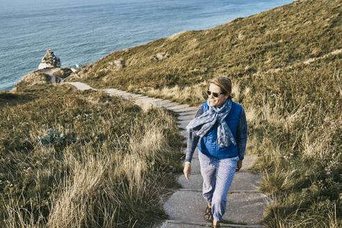 Frau, die im Urlaub an einem Steilufer am Meer spazieren geht - SSCF01017