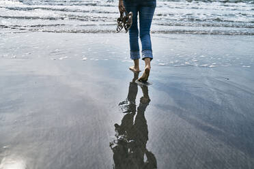 Woman walking on wet sand at beach - SSCF01054