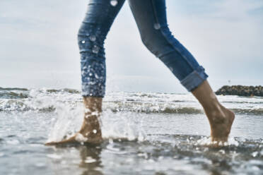 Woman running in water at beach - SSCF01063