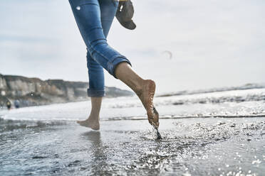 Woman running barefoot in sea at vacation - SSCF01065