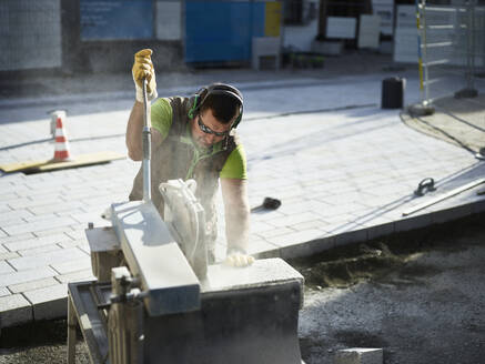 Handwerker beim Schneiden von Pflastersteinen auf einer Industrieanlage - CVF01933