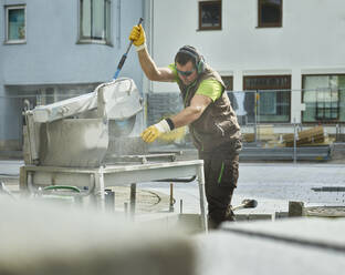 Bauarbeiter beim Schneiden von Pflastersteinen mit Maschinen auf der Baustelle - CVF01940