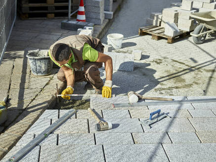 Arbeiter misst Pflastersteine auf der Baustelle aus - CVF01942