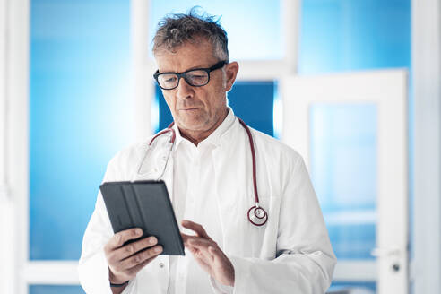 Oberarzt mit Stethoskop und digitalem Tablet-PC in einer Klinik - JOSEF07268