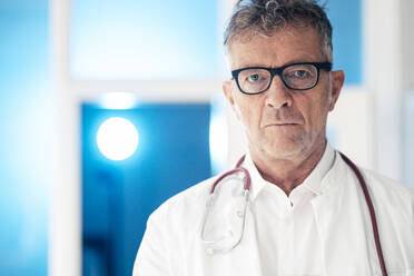 Oberarzt mit Brille, stehend mit Stethoskop in einer Klinik - JOSEF07269