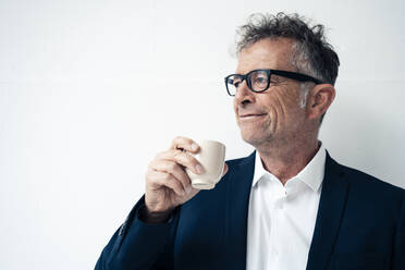 Lächelnder Geschäftsmann mit Kaffee vor weißem Hintergrund - JOSEF07302