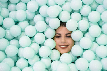 Smiling woman amidst blue balls - DLTSF02722