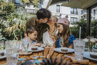 Parents kissing by children on party at back yard - MFF08570