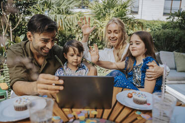 Familie winkt bei Videoanruf über Tablet-PC im Hinterhof - MFF08578