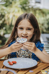 Smiling girl having cupcake on birthday party - MFF08582
