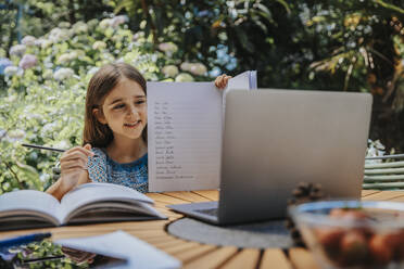 Mädchen zeigt Hausaufgaben durch Laptop im Hinterhof - MFF08591
