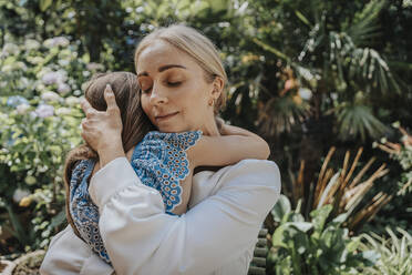 Mother embracing daughter in back yard - MFF08598