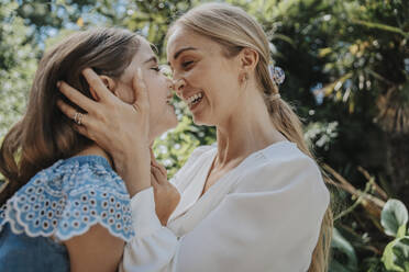 Happy mother and daughter rubbing noses in back yard - MFF08601