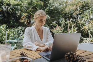 Geschäftsfrau arbeitet am Laptop im Hinterhof - MFF08605