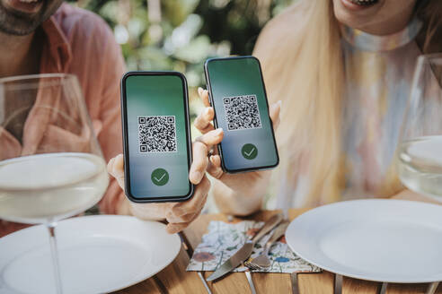 Couple showing QR codes of green passes on their smart phones - MFF08614