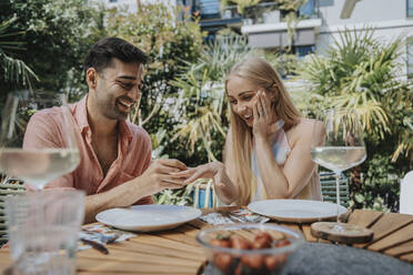 Man proposing woman with ring at outdoor table - MFF08616