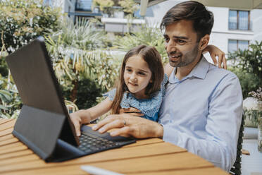 Lächelnder Vater und Tochter verwenden Tablet-Computer im Garten - MFF08626