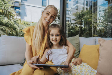 Lächelnde Mutter und Tochter mit Tablet-PC im Innenhof - MFF08633