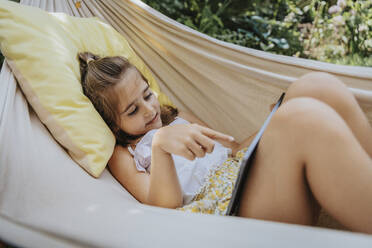 Girl with tablet PC lying in hammock - MFF08640