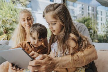 Vater und Kinder benutzen Tablet-Computer im Innenhof - MFF08645