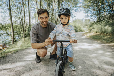 Lächelnder Vater und Sohn mit Fahrrad auf der Straße - MFF08666