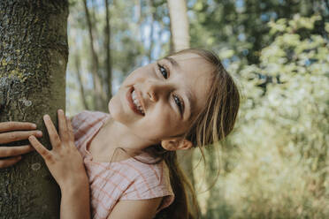 Smiling girl hugging tree in nature - MFF08676