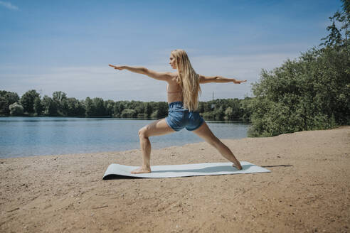 Frau übt am Wochenende Yoga am Seeufer - MFF08690