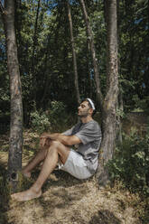 Mann sitzt inmitten von Bäumen in der Natur - MFF08691