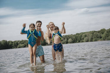 Fröhliche Eltern mit Kindern, die am Wochenende im See stehen - MFF08693