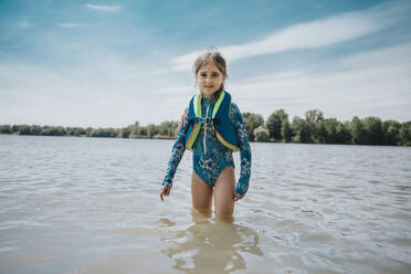 Mädchen mit Rettungsschwimmerjacke im See stehend - MFF08696