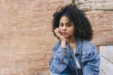 Afro woman sitting with hand on chin - DGOF02299